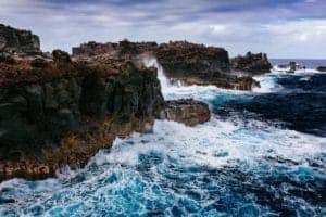 Ocean waves crashing against rocky cliffs during stormy weather.