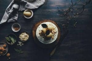 Delicious pear and chocolate dessert garnished with dark leaves, served on a wooden platter.
