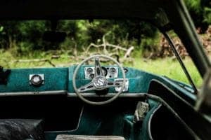 Old car dashboard and steering wheel in a vintage vehicle.