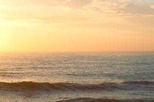 Sunset over the ocean with warm colors and gentle waves.